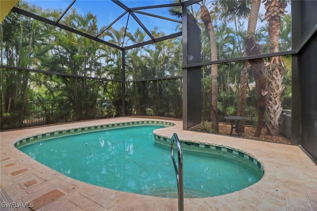 outdoor pool featuring glass enclosure and a patio