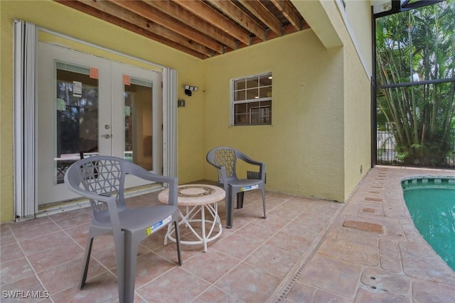 view of patio / terrace featuring glass enclosure, an outdoor pool, and french doors