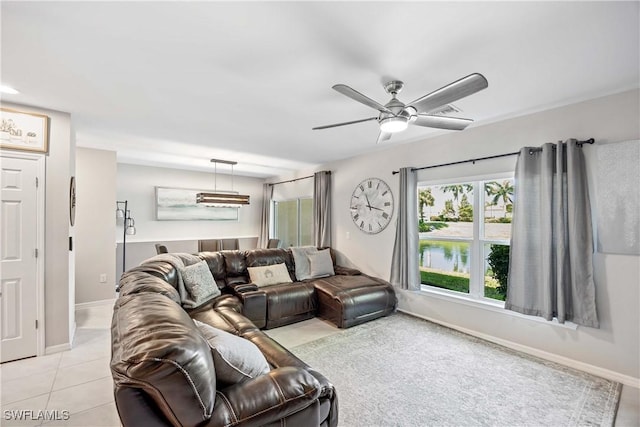 living area featuring light tile patterned flooring, ceiling fan, and baseboards