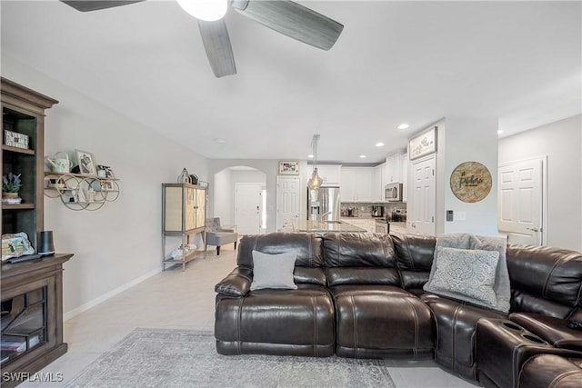 living area featuring arched walkways, recessed lighting, baseboards, and light tile patterned flooring