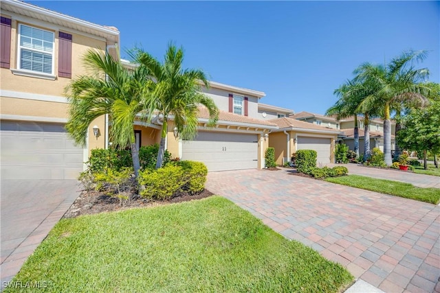 view of front of home with decorative driveway, a garage, and stucco siding