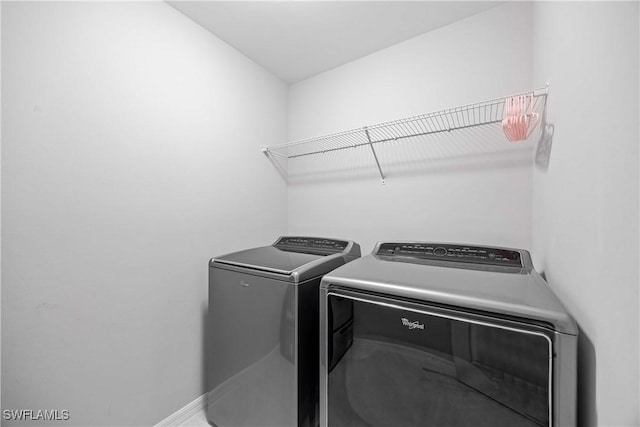 clothes washing area with baseboards, laundry area, and washer and clothes dryer