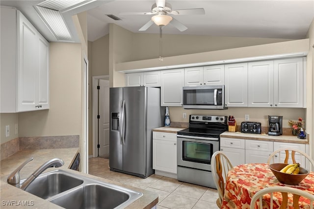 kitchen with lofted ceiling, a sink, visible vents, white cabinets, and appliances with stainless steel finishes