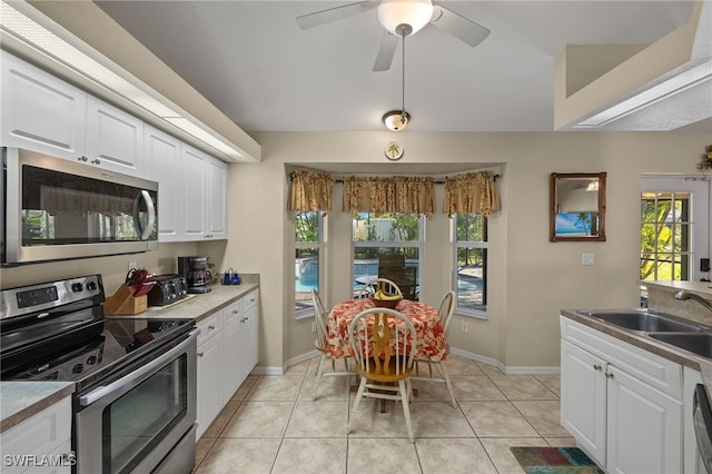 kitchen with appliances with stainless steel finishes, white cabinetry, a sink, ceiling fan, and light tile patterned flooring