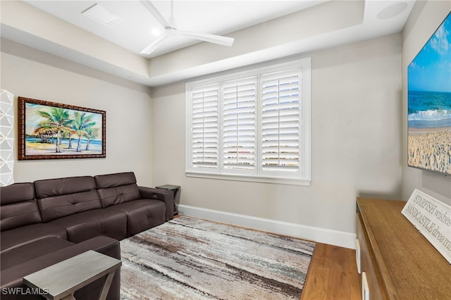 living area with a ceiling fan, visible vents, wood finished floors, and baseboards