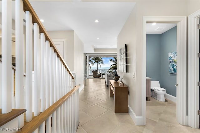 corridor featuring stairs, light tile patterned floors, recessed lighting, and baseboards