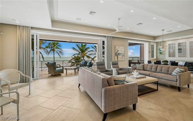 living area with light tile patterned flooring, a tray ceiling, and visible vents
