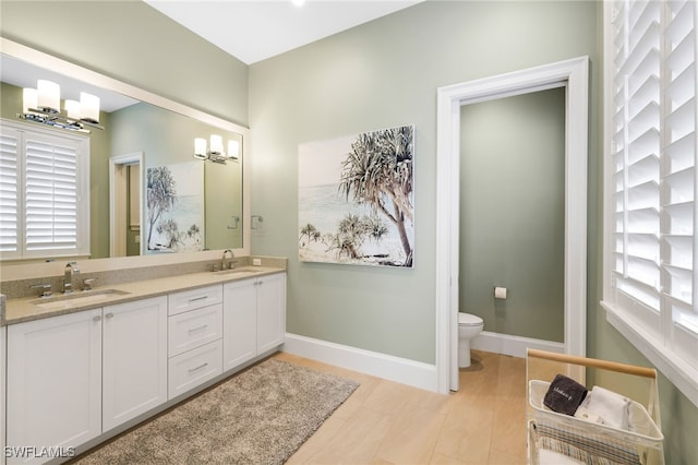 full bathroom featuring double vanity, toilet, baseboards, and a sink