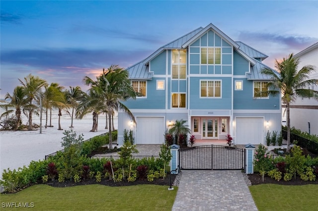 view of front of house featuring a gate, a standing seam roof, a fenced front yard, decorative driveway, and metal roof