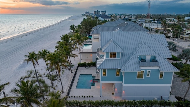 aerial view at dusk with a beach view and a water view