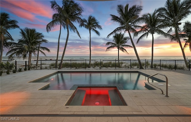 view of pool with a fenced in pool, an in ground hot tub, fence, and a water view