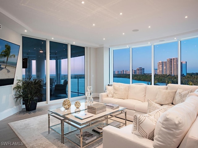 living area with a water view, expansive windows, recessed lighting, wood finished floors, and a view of city