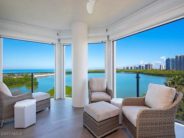 sunroom / solarium with a water view, plenty of natural light, a city view, and a ceiling fan