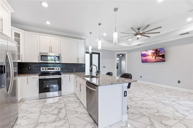 kitchen featuring ornamental molding, a peninsula, stainless steel appliances, a raised ceiling, and a sink