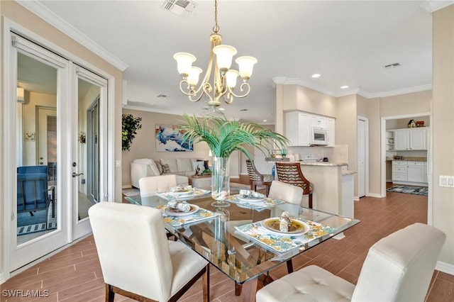 dining space with crown molding, a notable chandelier, visible vents, and wood tiled floor