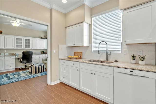 kitchen with built in desk, ornamental molding, white cabinetry, a sink, and dishwasher