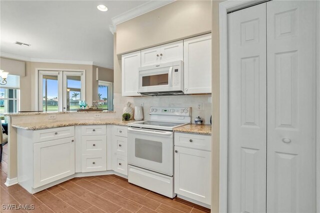 kitchen featuring a peninsula, white appliances, visible vents, and crown molding