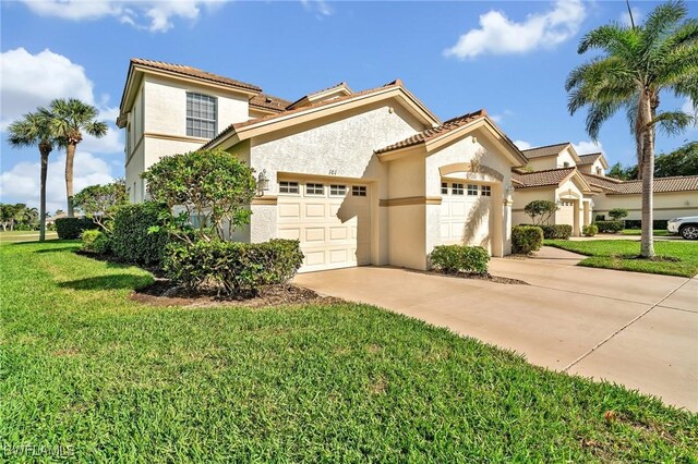 mediterranean / spanish-style home featuring an attached garage, driveway, a front yard, and stucco siding