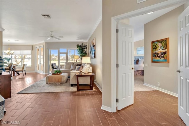 interior space featuring ornamental molding, wood finished floors, visible vents, and baseboards