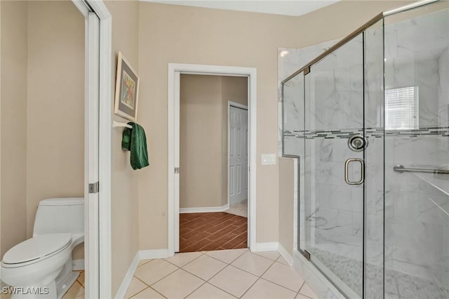 full bath with toilet, a marble finish shower, and baseboards