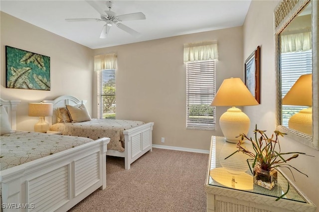 bedroom featuring multiple windows, baseboards, a ceiling fan, and light colored carpet