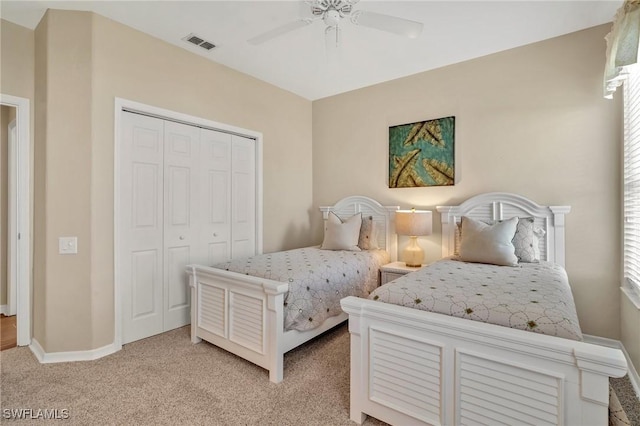 bedroom featuring baseboards, visible vents, light colored carpet, ceiling fan, and a closet