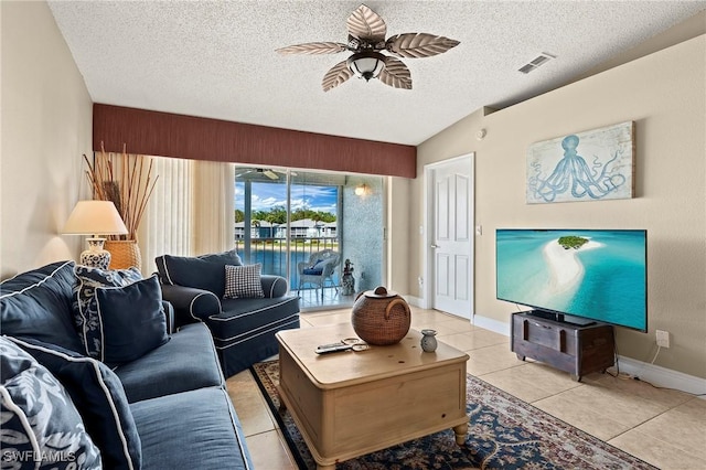 living area with light tile patterned floors, visible vents, a ceiling fan, lofted ceiling, and a textured ceiling