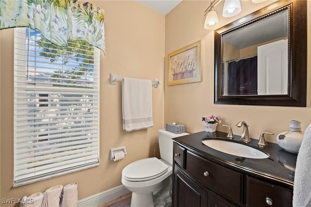 bathroom with toilet, vanity, and baseboards