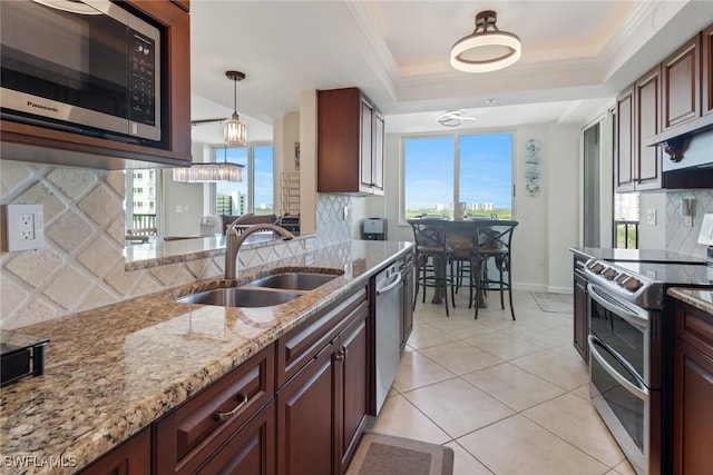 kitchen featuring light tile patterned floors, a raised ceiling, stainless steel appliances, crown molding, and a sink