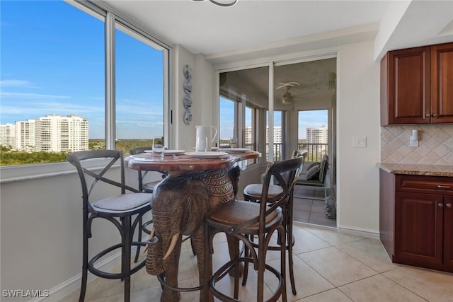 dining room featuring a view of city, a healthy amount of sunlight, baseboards, and light tile patterned floors