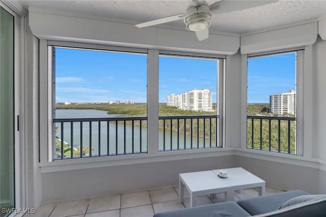 unfurnished sunroom with a water view, ceiling fan, and a view of city