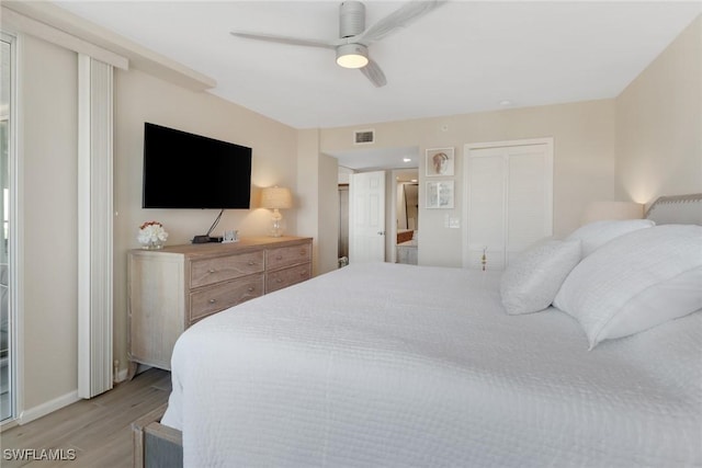 bedroom featuring ceiling fan, visible vents, baseboards, light wood finished floors, and ensuite bath