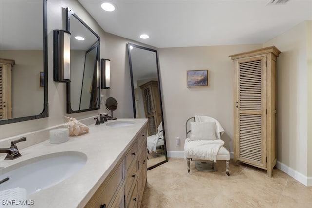 bathroom with double vanity, baseboards, a sink, and recessed lighting