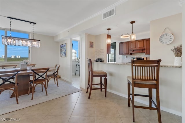 dining area featuring a wealth of natural light, visible vents, crown molding, and light tile patterned floors