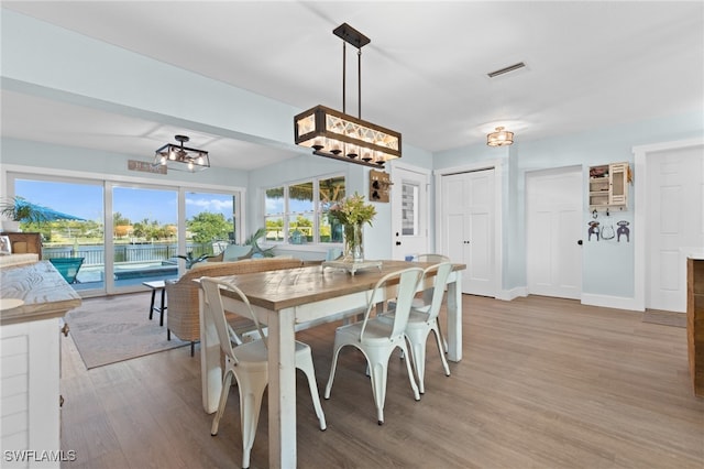 dining space featuring light wood-style floors, visible vents, and baseboards