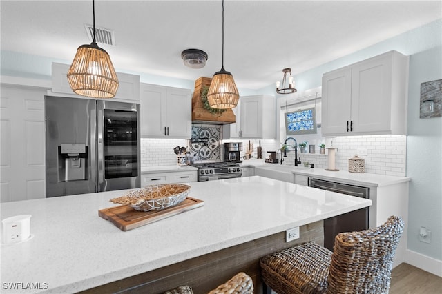 kitchen with visible vents, a kitchen bar, a sink, backsplash, and appliances with stainless steel finishes