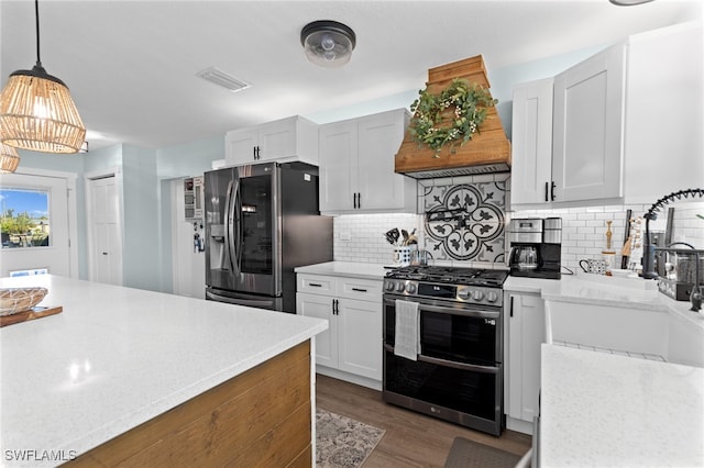 kitchen with custom range hood, a sink, tasteful backsplash, appliances with stainless steel finishes, and dark wood-style flooring