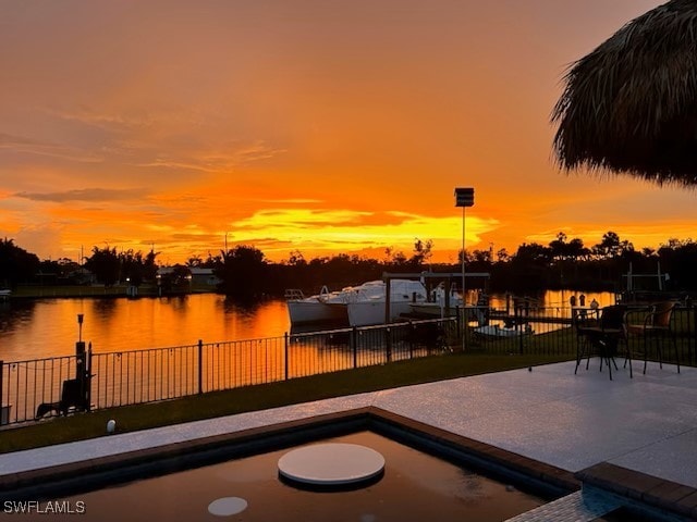 view of patio with fence and a water view