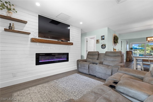 living room featuring a glass covered fireplace, wooden walls, recessed lighting, and wood finished floors