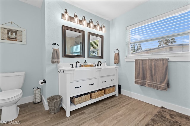 full bathroom with double vanity, toilet, wood finished floors, and baseboards