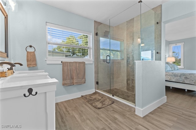 ensuite bathroom with a stall shower, a sink, wood finished floors, connected bathroom, and baseboards