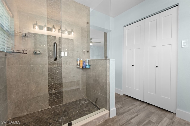 bathroom featuring a tile shower, ceiling fan, baseboards, and wood finished floors