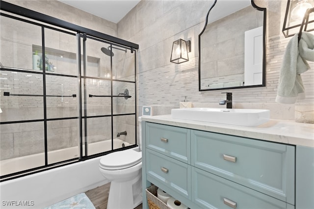 bathroom featuring vanity, wood finished floors, tile walls, toilet, and combined bath / shower with glass door