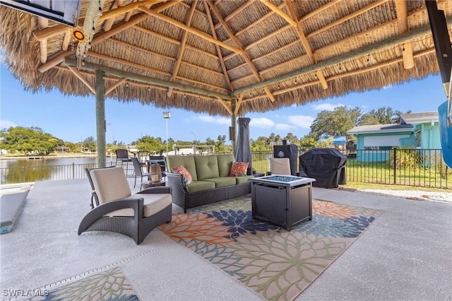 view of patio / terrace featuring a water view, fence, a gazebo, grilling area, and an outdoor living space with a fire pit