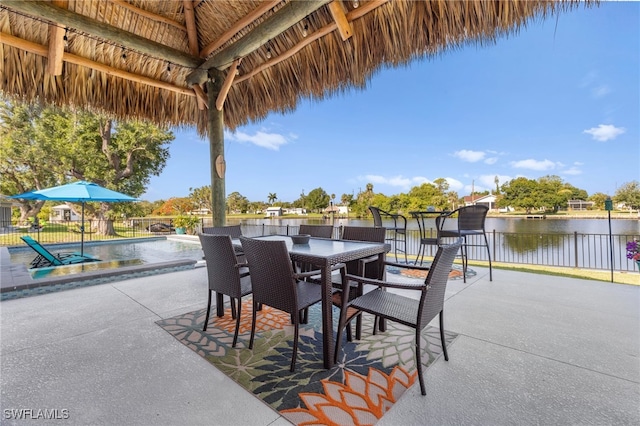 view of patio featuring outdoor dining area, fence, a fenced in pool, and a water view