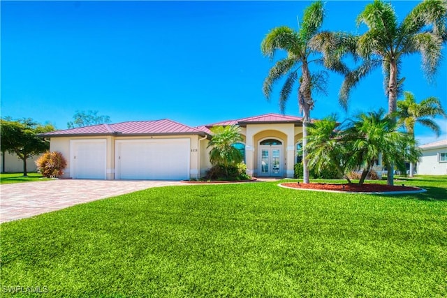 mediterranean / spanish-style house featuring stucco siding, a standing seam roof, decorative driveway, french doors, and a front yard