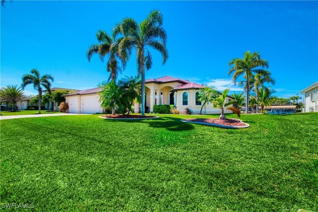 mediterranean / spanish house featuring an attached garage, metal roof, concrete driveway, and a front yard