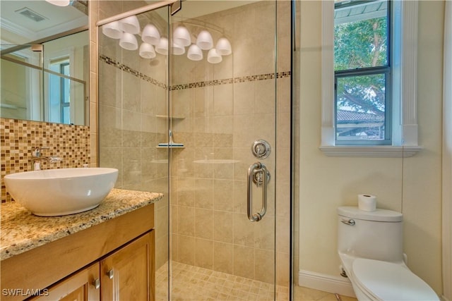 bathroom with a stall shower, visible vents, toilet, vanity, and backsplash