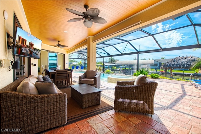 view of patio / terrace with an outdoor pool, a ceiling fan, an in ground hot tub, a lanai, and an outdoor living space