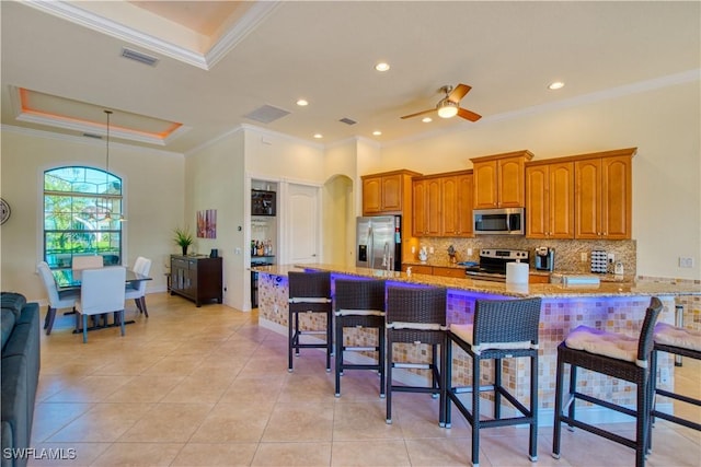 kitchen featuring light stone counters, brown cabinets, visible vents, appliances with stainless steel finishes, and a kitchen bar